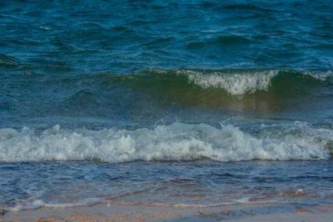Small sea waves hitting sandy shore  Stock Photos