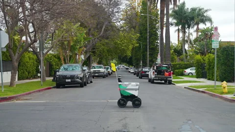 Small self-driving robot crossing the street in quiet neighborhood Stock Footage 243639498