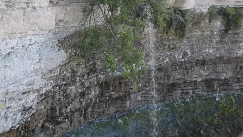A small, serene waterfall cascades from rocks in a nature video in the forest. Stock Footage 343662500