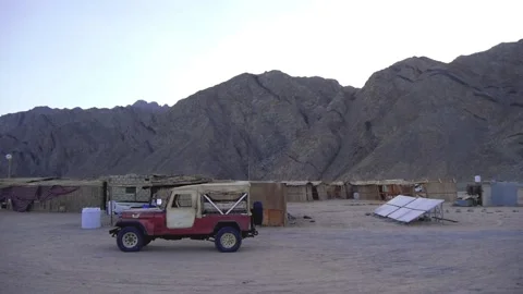 Small Settlement In A Desert Area With Reed Huts, Old Car And Solar Panels Stock Footage 226962598