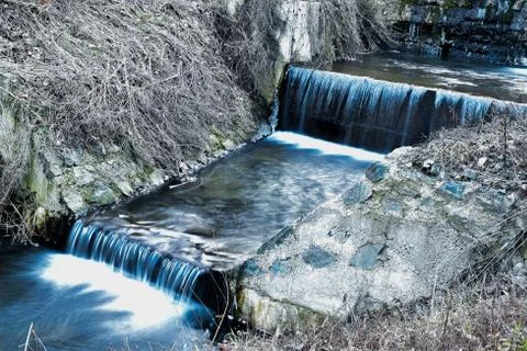 Small shallow blue stream with two watterfalls Stock Photos