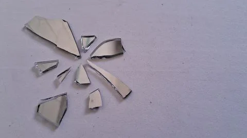 Small sharp shards of broken mirror scattered on white surface Stock Photos