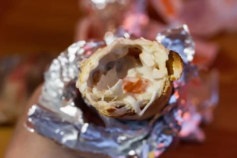 A small shawarma in foil after a bite is viewed from above. Junk food. Stock Photos