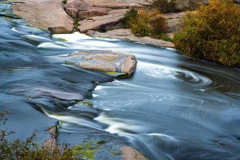A small shining stream flows among smooth wet and dark stones Stock-Fotos