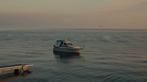 Small ship sailing on calm water by shore at sunset, with another ship visible Stock Footage 314491422