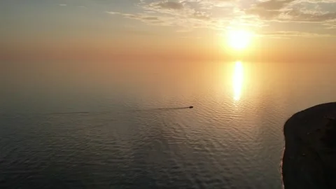 A small ship sails in the sea at sunset, a huge yellow sun goes below the 库存影片 256599696