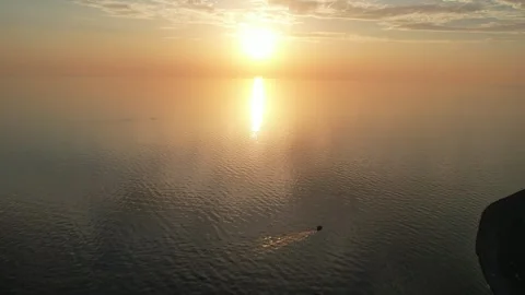 A small ship sails in the sea at sunset, a huge yellow sun goes below the Video stock 256599723