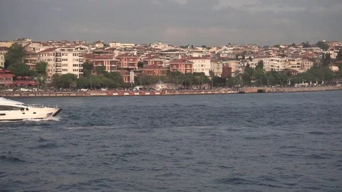 A small ship slowly floating on the coastal area near the city. On the horizon Stock Footage 109479809