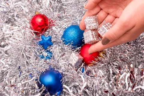Small silver gift boxes in hand on the background of tinsel and Christmas toy Stock Photos