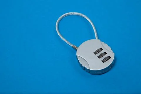 Small silver iron cipher lock with a coded set on blue background Foto stock