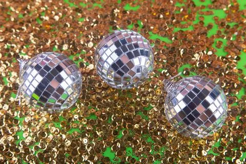Small silver shining disco balls with reflections, glare on the blurred golden Stock Photos