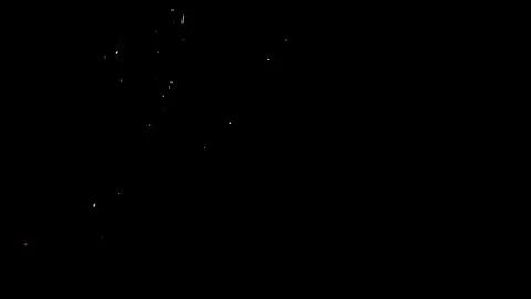 Small silver sparks fall vertically against deep black background Stock Footage 327581469