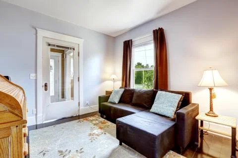 Small simple room with couch and floral rug Stock Photos