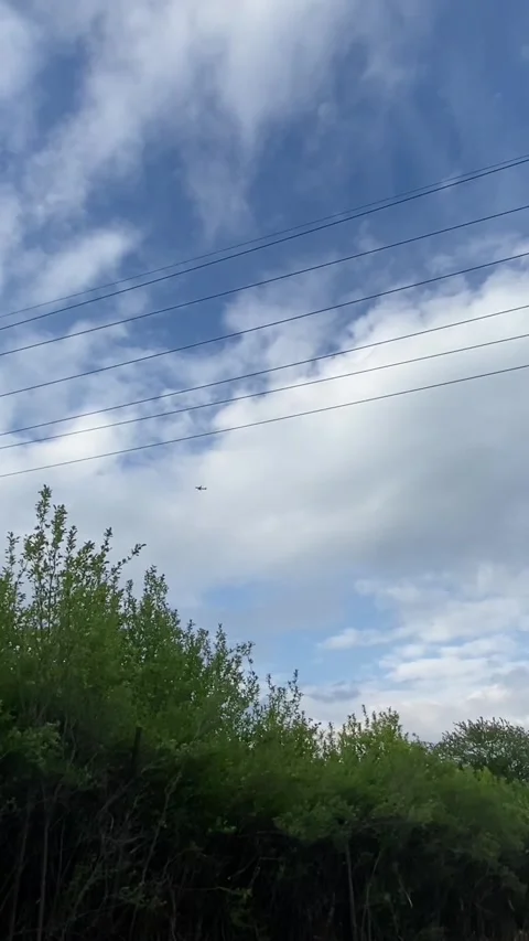 Small single-engine airplane flying over suburban sky with power lines and green Vidéo 336534228