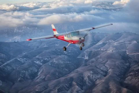 Small single engine airplane flying in the gorgeous sunset sky through the sea Stock Photos