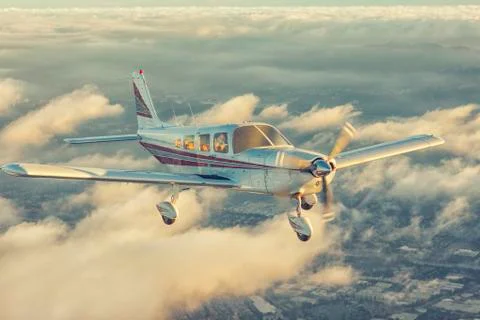 Small single engine airplane flying in the gorgeous sunset sky through the sea 스톡 사진