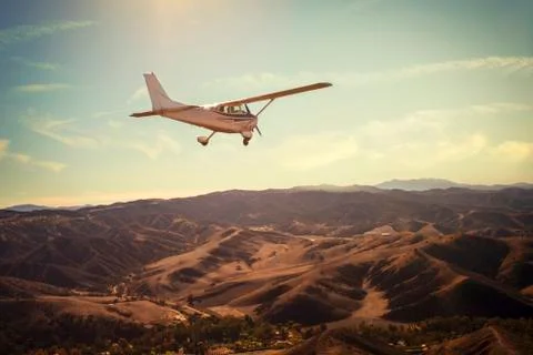 Small single engine airplane flying in the gorgeous sunset sky above the Stock-Fotos