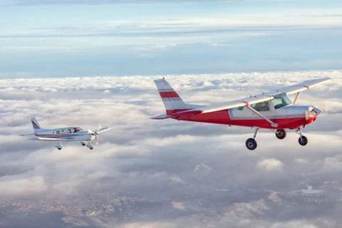 Small single engine airplane flying in the gorgeous sunset sky through the sea Stock Photos