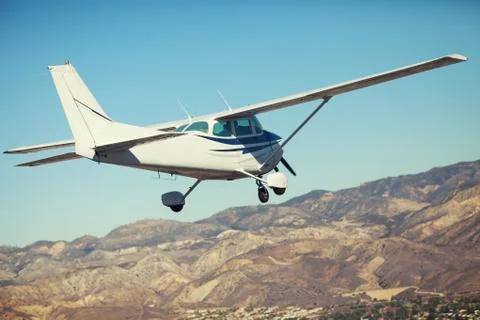 Small single engine airplane flying in the gorgeous sunset sky through the sea Stock Photos