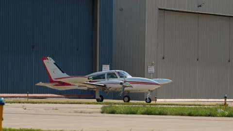 A small single-engine airplane is parked near a hangar on a sunny day at a Stock Footage 325694401
