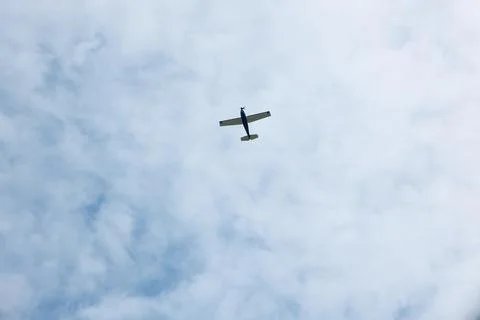 Small Single-Engine Propeller Plane Flying in Blue Sky with White Clouds Stock Photos