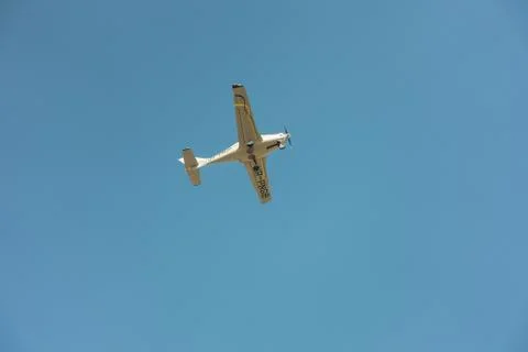 Small single-propeller plane flying low in the blue sky 库存照片
