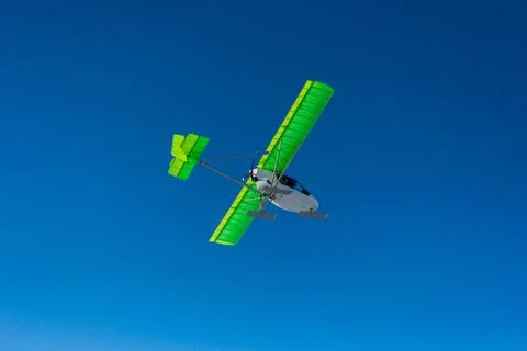 Small single-propeller plane flying over the blue sky. Stock Photos