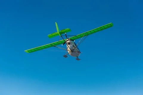 Small single-propeller plane flying over the blue sky. Stock Photos