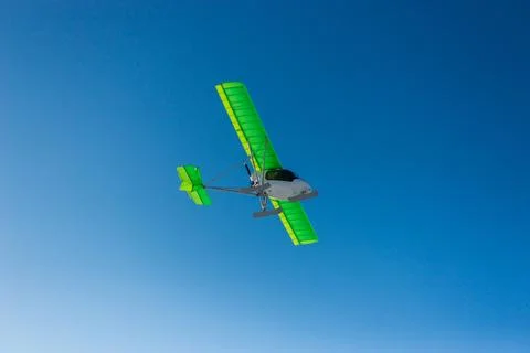Small single-propeller plane flying over the blue sky. Stock Photos