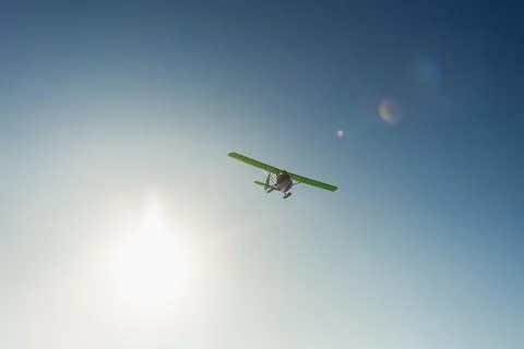 Small single-propeller plane flying over the blue sky. Stock Photos