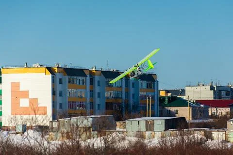 Small single-propeller plane flying over the blue sky. Stock Photos