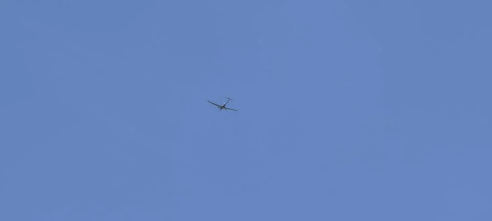 Small single‑engine airplane flying high against a clear blue sky Fotos Stock