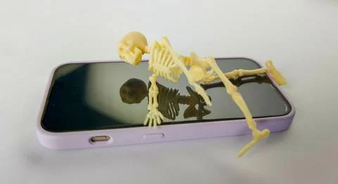 Small skeleton model positioned on a smartphone screen, illustrating the them Stock Photos