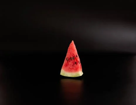 Small slice of watermelon on a black background. Stock Photos