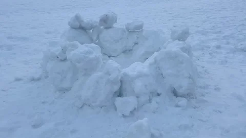 Small snow fort or wall made of piled snowballs on snowy ground. Winter fun and Stock Footage 323533243