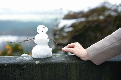 A small snowman with branches instead of arms and a human hand holding a bran Stock Photos