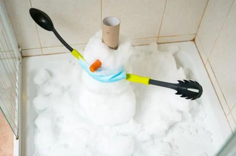 Small snowman built inside a shower with cutlery for hands. Stock Photos