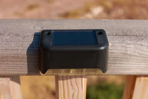 Small solar powered led light with motion sensor on wooden terrace Stock Photos