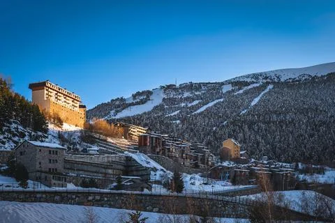 Small Soldeu town surrounded by pine forest and snow capped mountain range Stock Photos