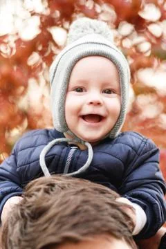 A small son sits on the shoulders of a young father Stock Photos