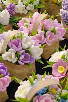 Small spring bouquets made of artificial flowers in wicker wooden baskets Stock Photos
