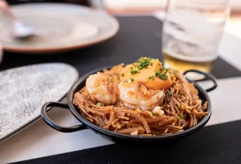 Small spring noodles with large prawns and piquillo pepper sauce Stock Photos