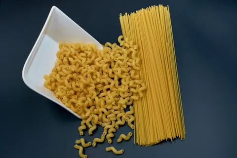 Small spring-shaped pasta is poured out of a white saucer. Spaghetti pasta on Stock Photos