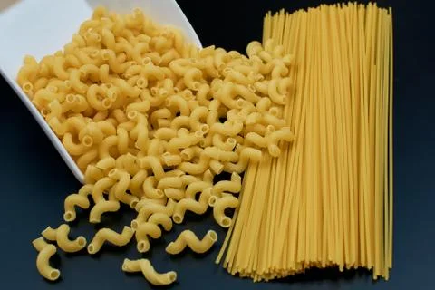 Small spring-shaped pasta is poured out of a white saucer. Spaghetti pasta on Stock Photos