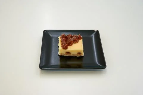 A small square of cake with chocolate chips on top Stock Photos