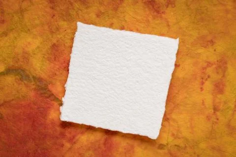 Small square sheet of blank white Khadi paper against colorful marbled paper Stock Photos