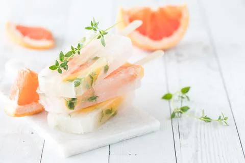 A small stack of grapefruit thyme popsicles on a white wood slate table. 스톡 사진