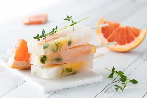 A small stack of grapefruit thyme popsicles on a white slate board table. Foto stock