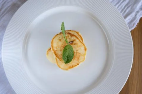 Small stack of pancakes garnished with mint on white plate Stock Photos