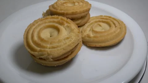 A small stack of round butter cookies with a spiral pattern rotates slowly .. Stock Footage 328485591